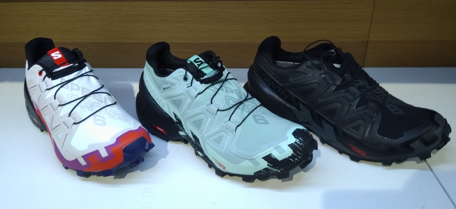 店頭の白い台に並んだ、Salomon のトレイルランニングシューズ Speedcross の3足(白、ミント、黒)。2022年に撮影された現行モデルで、本文に出てくる2015年の共同企画の靴とは別のもの